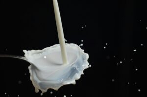 Capturing a dynamic splash of milk on a spoon in mid-air with dark background.
