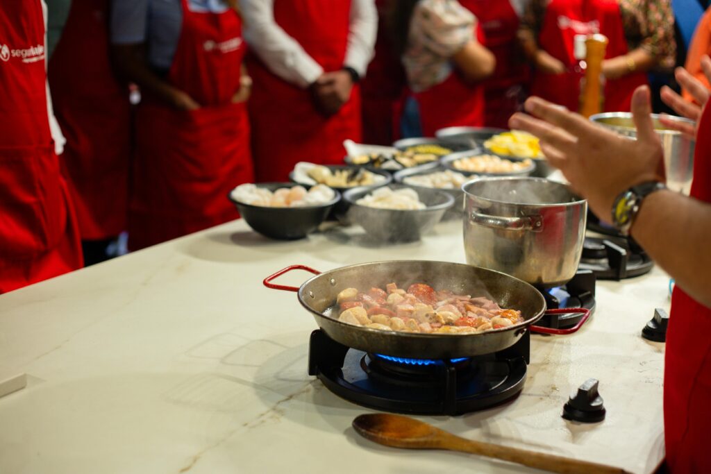 Participants learn cooking skills in a vibrant class setting, engaging with hands-on food preparation.