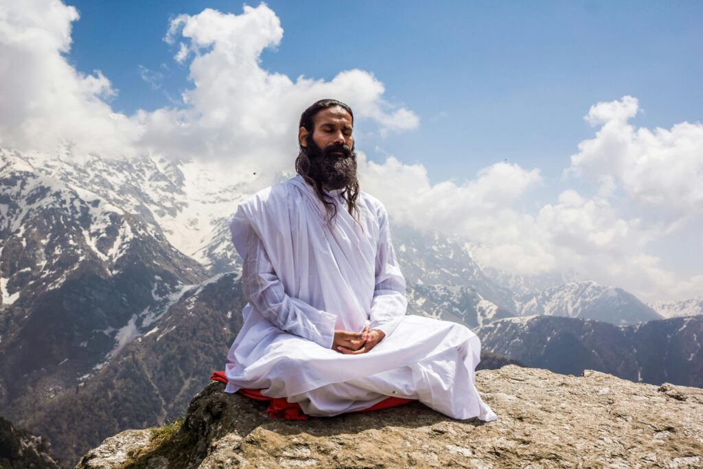 A man in traditional attire meditates in the serene Himalayan mountains at Kedarnath.