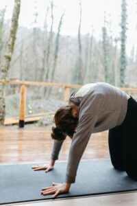 A woman performs the yoga cat pose indoors on a mat, promoting mindfulness and fitness.