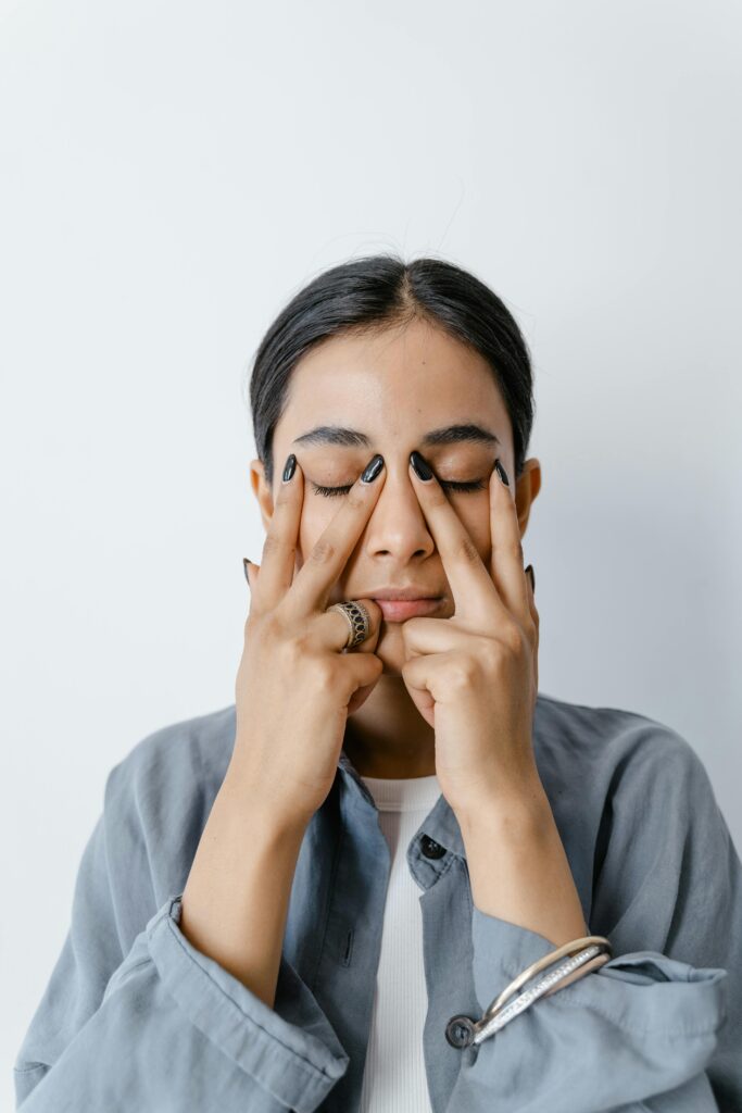 Woman practicing facial yoga for relaxation and skincare routine indoors.
