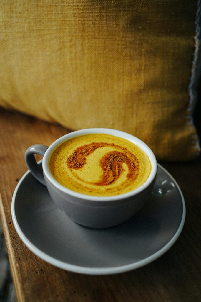 Warm turmeric latte with cinnamon froth art, served in a cozy indoor setting.