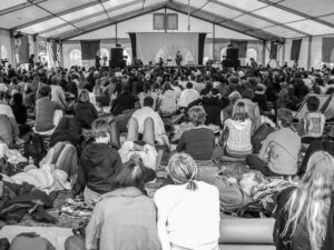 Black and white photo of a large crowd attending a yoga meditation session in Berlin under a tent.