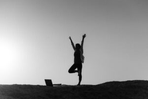 Black and white image of a woman doing yoga outdoors, highlighting tranquility.