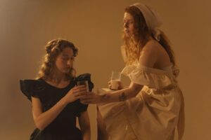 Creative studio shoot of two women in vintage dresses, sharing milk.