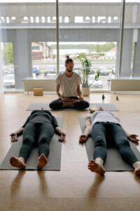 Instructor guides meditation for adults in yoga class with relaxation pose indoors.