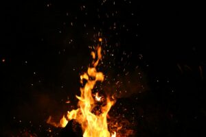 Mesmerizing campfire flames and sparks against a dark nighttime backdrop.