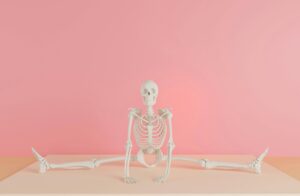 A human skeleton model does a split against a pink backdrop, showcasing flexibility.