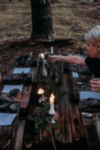 From above of crop young female at timber table with glasses of wine and decorated with candles and green leaves
