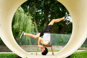 Man balances in a yoga headstand using a chair outdoors in Bratislava, showcasing flexibility and strength.
